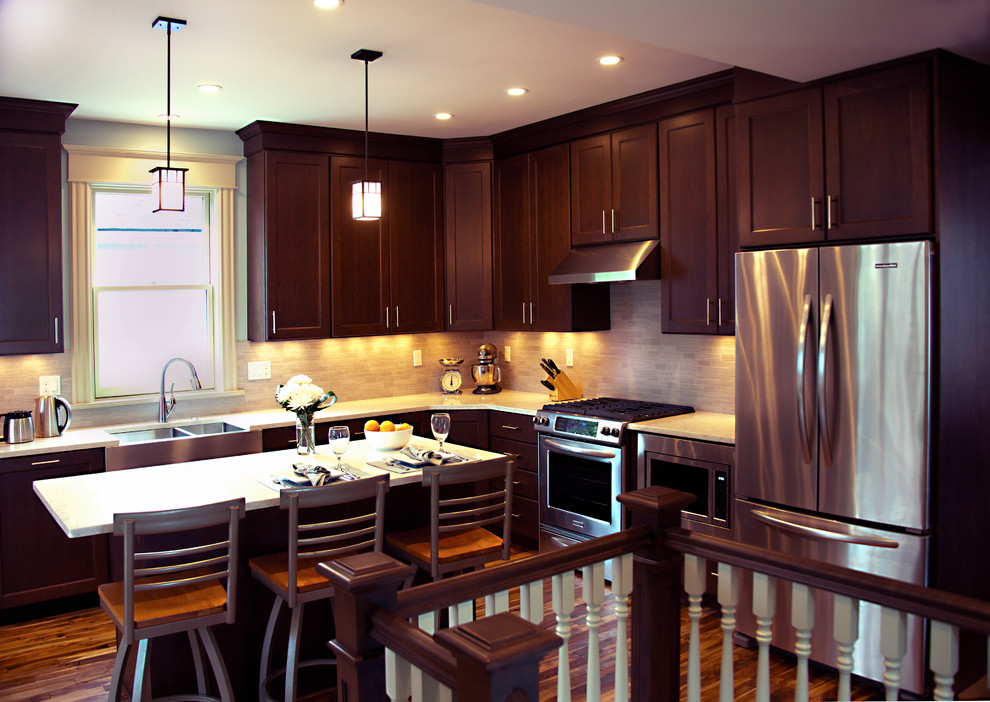 Inspiration for a transitional l-shaped dark wood floor eat-in kitchen remodel in Grand Rapids with a farmhouse sink, shaker cabinets, dark wood cabinets, quartz countertops, gray backsplash, stone tile backsplash, stainless steel appliances and an island