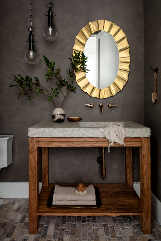 Inspiration for a small farmhouse travertine floor and brown floor powder room remodel in DC Metro with black walls, an integrated sink, concrete countertops, gray countertops, a freestanding vanity, open cabinets and medium tone wood cabinets