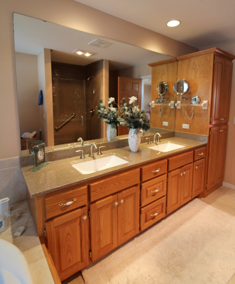 Inspiration for a large traditional master bathroom in Minneapolis with raised-panel cabinets, medium wood cabinets, a drop-in tub, an alcove shower, a two-piece toilet, beige walls, ceramic floors, an integrated sink, onyx benchtops, beige floor and a hinged shower door.
