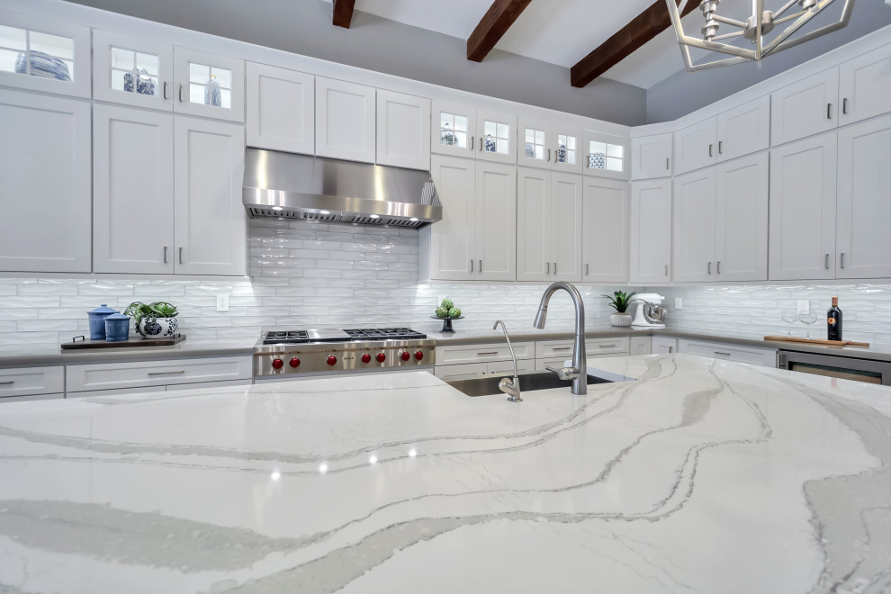 Example of a large transitional l-shaped porcelain tile and brown floor eat-in kitchen design in Phoenix with a farmhouse sink, shaker cabinets, white cabinets, quartz countertops, white backsplash, subway tile backsplash, stainless steel appliances, an island and gray countertops