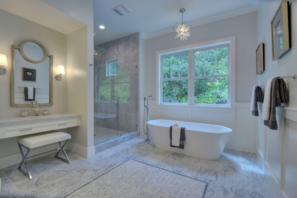 Photo of a large traditional master bathroom in San Francisco with shaker cabinets, white cabinets, a freestanding tub, a double shower, gray tile, stone tile, grey walls, marble floors, marble benchtops, grey floor, a hinged shower door and grey benchtops.