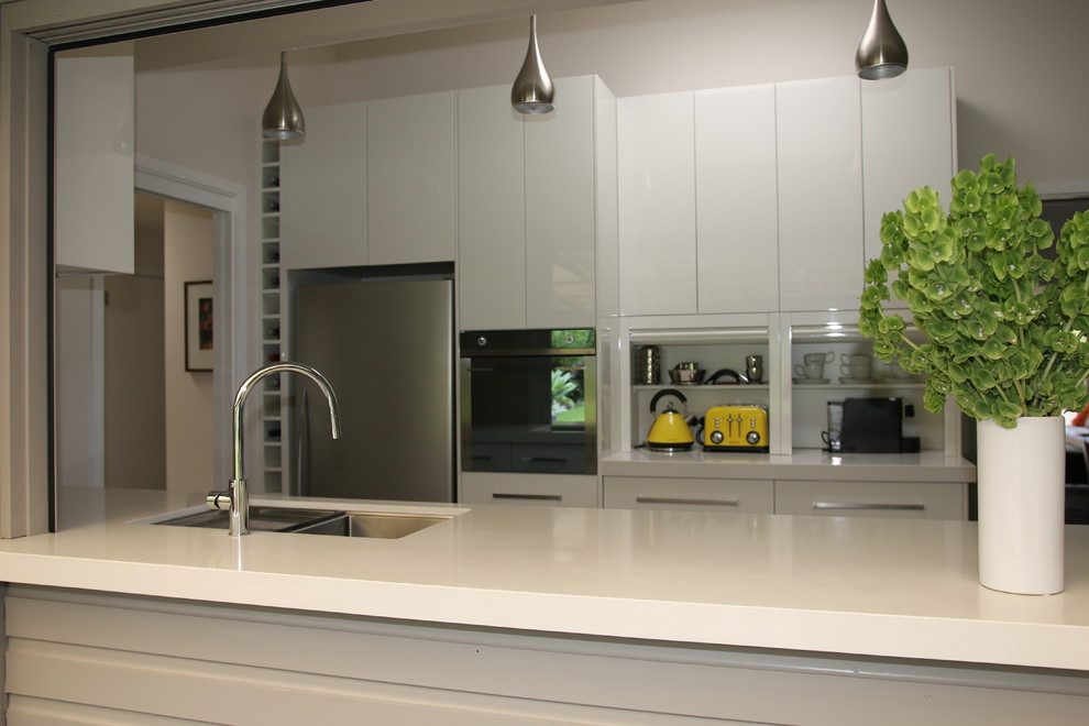 Exempel på ett stort modernt kök, med en undermonterad diskho, släta luckor, vita skåp, bänkskiva i kvarts, brunt stänkskydd, glaspanel som stänkskydd, rostfria vitvaror och skiffergolv