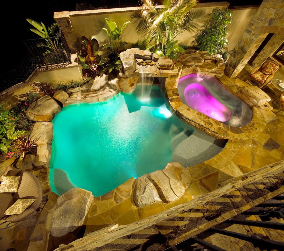 Mid-sized mediterranean backyard custom-shaped pool in Orange County with a hot tub and natural stone pavers.