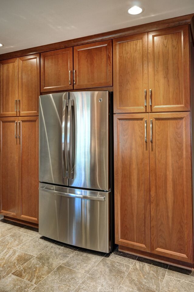 Inspiration for a mid-sized transitional l-shaped vinyl floor enclosed kitchen remodel in Milwaukee with an undermount sink, raised-panel cabinets, medium tone wood cabinets, granite countertops, gray backsplash, glass tile backsplash and stainless steel appliances