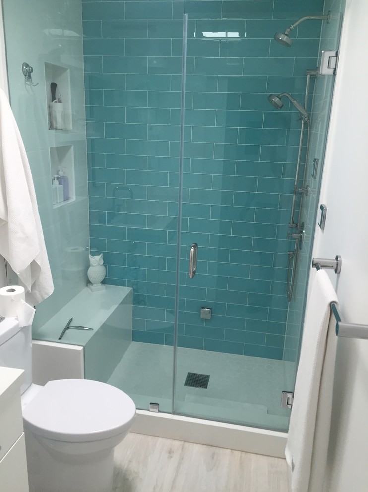Mid-sized modern master bathroom in Orange County with flat-panel cabinets, white cabinets, a freestanding tub, blue tile, glass tile, white walls and ceramic floors.