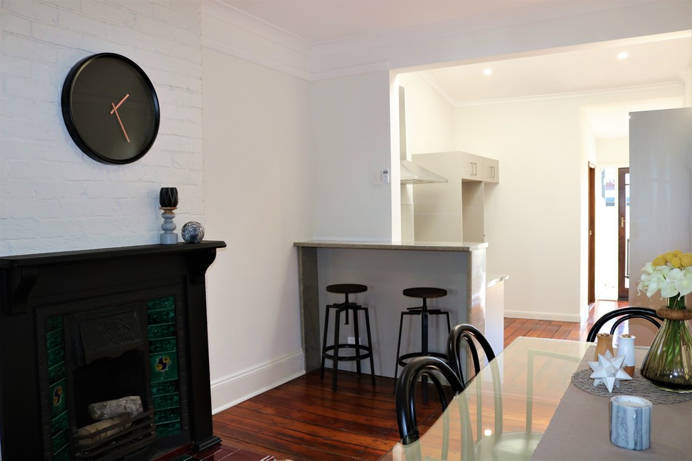 Photo of a small traditional open plan dining in Newcastle - Maitland with grey walls, light hardwood floors, a standard fireplace and a wood fireplace surround.