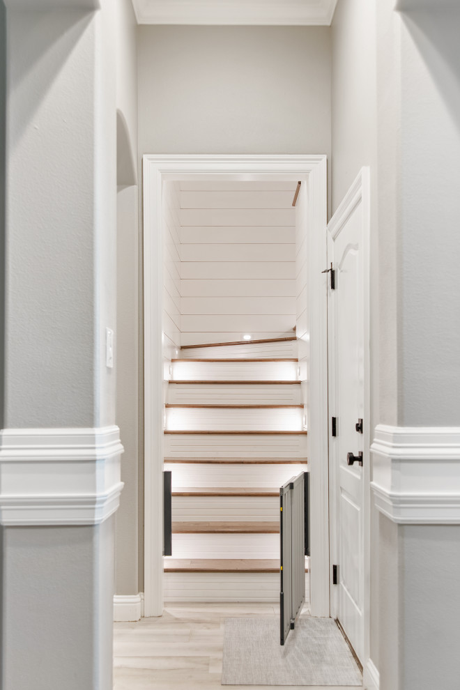 Пример оригинального дизайна: п-образная лестница среднего размера в стиле неоклассика (современная классика) с деревянными ступенями, крашенными деревянными подступенками, металлическими перилами и стенами из вагонки