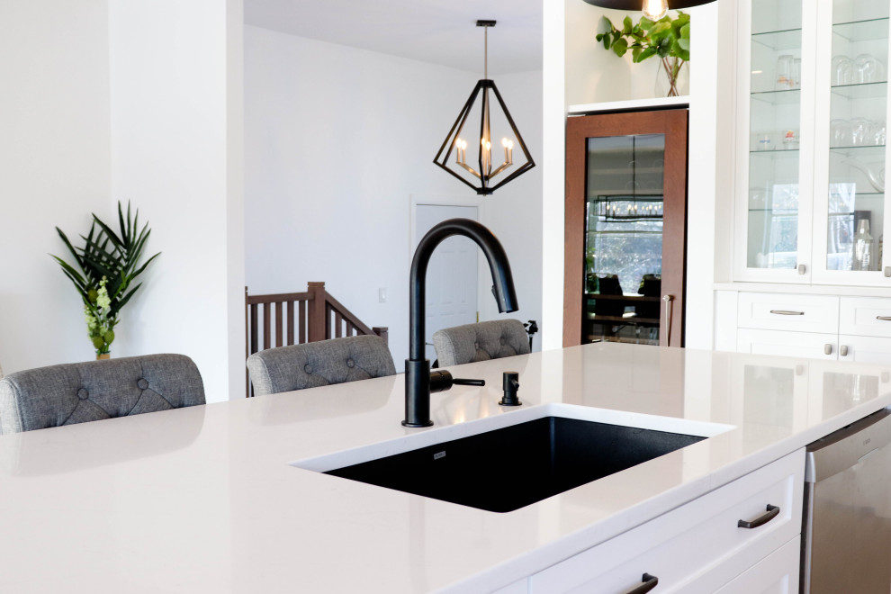 Open concept kitchen - large transitional l-shaped medium tone wood floor and brown floor open concept kitchen idea with an undermount sink, shaker cabinets, white cabinets, quartzite countertops, white backsplash, ceramic backsplash, stainless steel appliances and an island