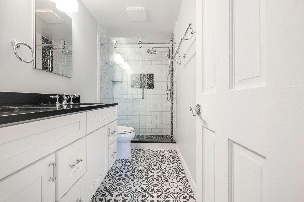 Inspiration for a mid-sized country master bathroom in DC Metro with shaker cabinets, white cabinets, an alcove shower, a two-piece toilet, white tile, subway tile, grey walls, porcelain floors, an undermount sink, engineered quartz benchtops, multi-coloured floor, a sliding shower screen, black benchtops, a niche, a double vanity and a built-in vanity.