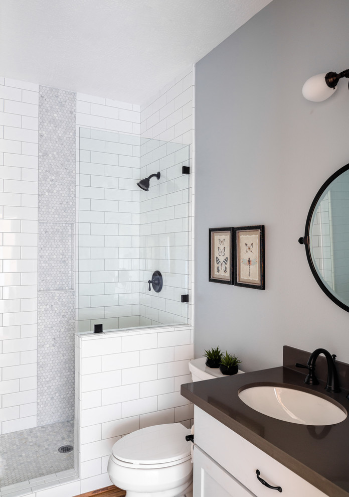 Design ideas for a mid-sized transitional bathroom in Houston with shaker cabinets, grey cabinets, a one-piece toilet, gray tile, ceramic tile, grey walls, vinyl floors, an undermount sink, engineered quartz benchtops, beige floor and a hinged shower door.