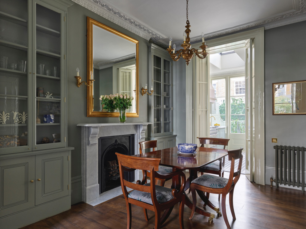 Inspiration for a large victorian kitchen/dining room in London with green walls, dark hardwood flooring, a standard fireplace, a stone fireplace surround, brown floors and a chimney breast.