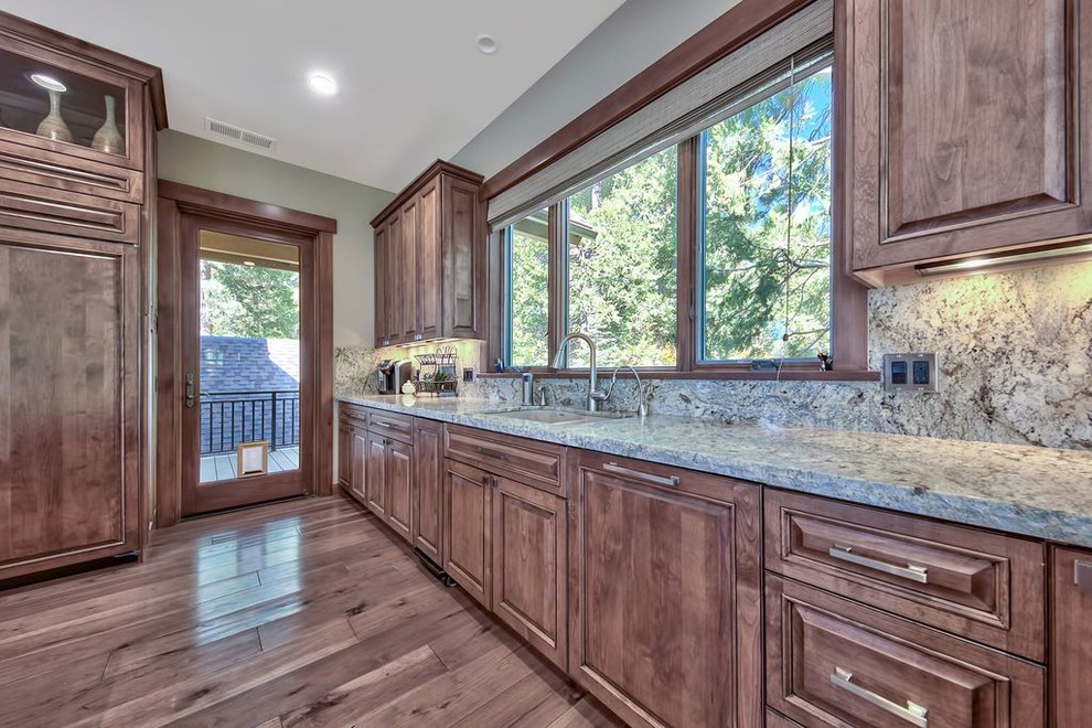 Example of a huge transitional u-shaped medium tone wood floor and multicolored floor open concept kitchen design with a double-bowl sink, raised-panel cabinets, medium tone wood cabinets, granite countertops, multicolored backsplash, stone slab backsplash, paneled appliances, an island and multicolored countertops