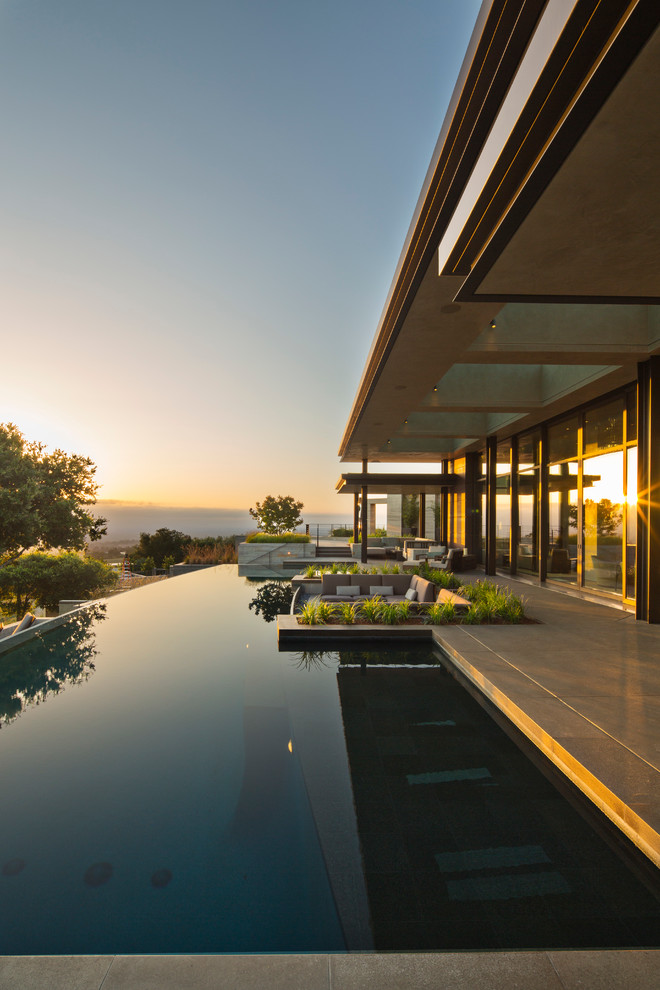 Expansive modern backyard custom-shaped infinity pool in San Francisco with a water feature and concrete slab.