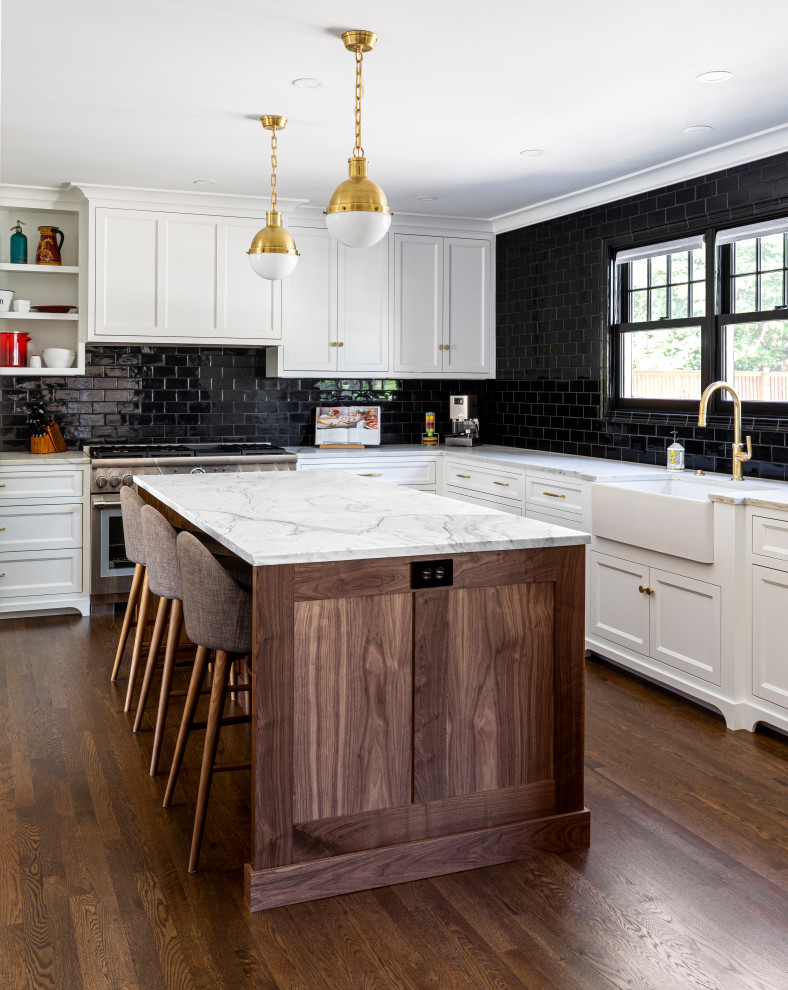 Inspiration for a large transitional medium tone wood floor and brown floor eat-in kitchen remodel in Portland with a farmhouse sink, white cabinets, marble countertops, black backsplash, subway tile backsplash, white appliances, an island and white countertops
