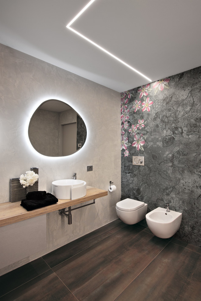 Пример оригинального дизайна: туалет среднего размера в современном стиле с светлыми деревянными фасадами, инсталляцией, серыми стенами, полом из керамогранита, настольной раковиной, столешницей из ламината, разноцветным полом и подвесной тумбой