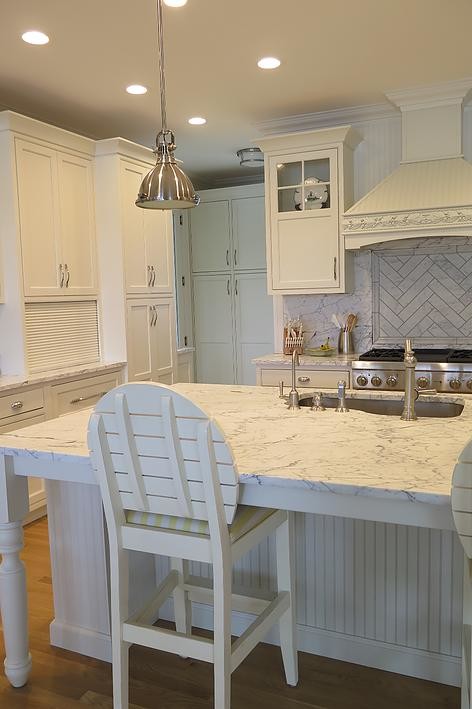 Mid-sized elegant l-shaped light wood floor eat-in kitchen photo with an undermount sink, shaker cabinets, white cabinets, white backsplash, stone tile backsplash, stainless steel appliances, an island and marble countertops