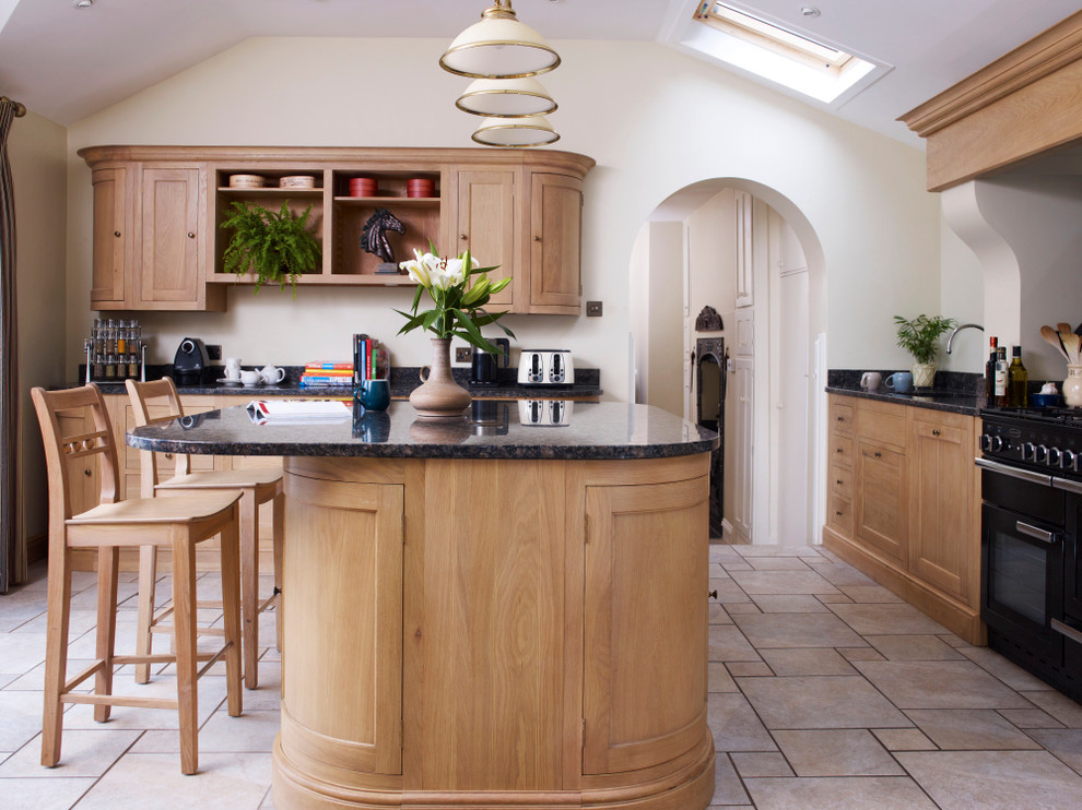 Inspiration for a large traditional u-shaped open plan kitchen in Devon with a double-bowl sink, shaker cabinets, light wood cabinets, granite benchtops, blue splashback, ceramic splashback, black appliances, limestone floors and with island.