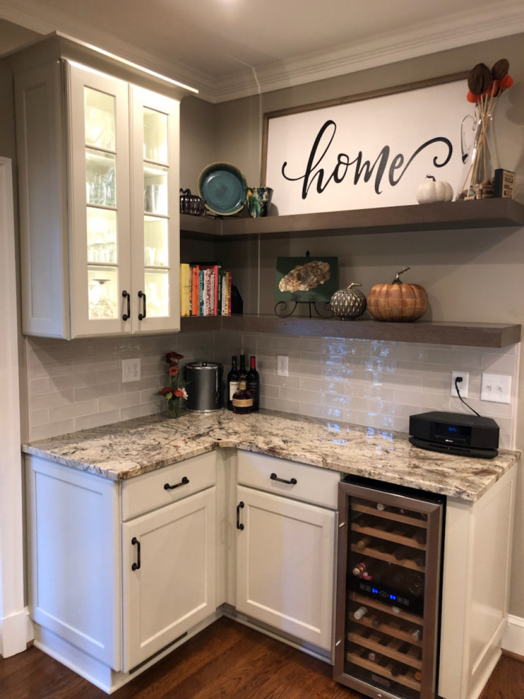 Mid-sized country l-shaped wet bar in Richmond with recessed-panel cabinets, white cabinets, granite benchtops, white splashback, subway tile splashback, medium hardwood floors, brown floor and multi-coloured benchtop.