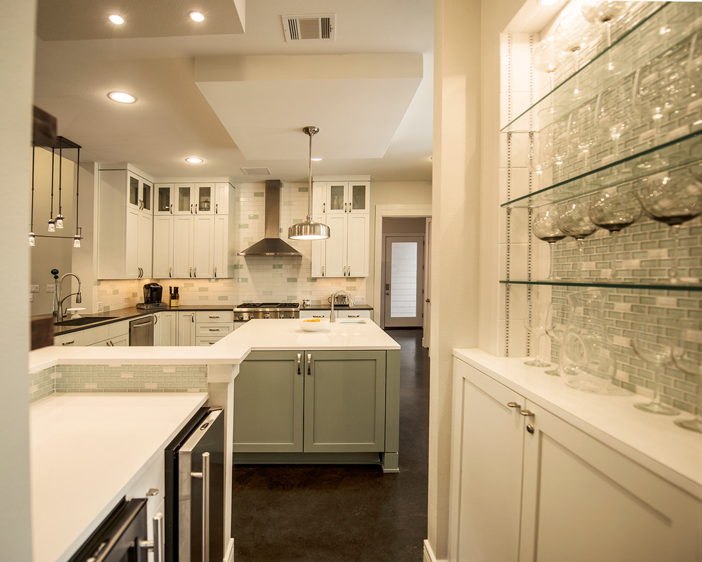 Example of a transitional concrete floor kitchen design in Austin with an undermount sink, shaker cabinets, white cabinets, multicolored backsplash, glass tile backsplash, stainless steel appliances, white walls and an island