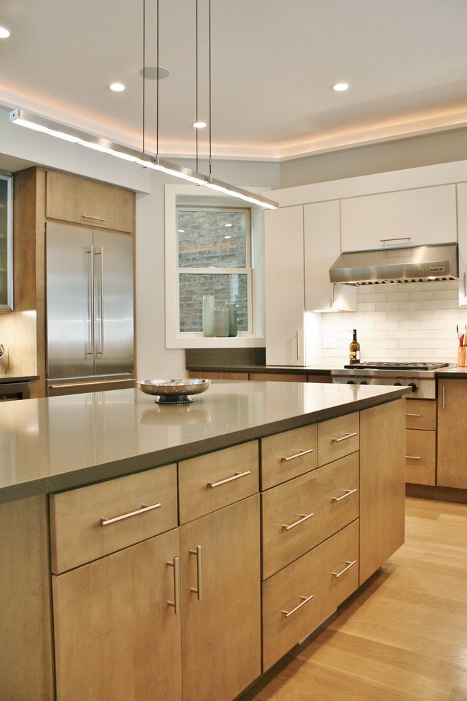 Inspiration for a large transitional u-shaped light wood floor kitchen remodel with an undermount sink, flat-panel cabinets, medium tone wood cabinets, quartz countertops, white backsplash, subway tile backsplash, stainless steel appliances and an island