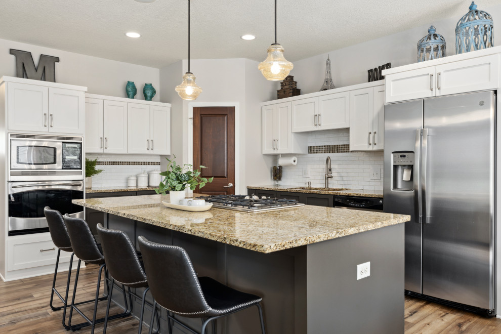 Eat-in kitchen - mid-sized transitional l-shaped vinyl floor and brown floor eat-in kitchen idea in Minneapolis with a double-bowl sink, shaker cabinets, white cabinets, granite countertops, white backsplash, ceramic backsplash, stainless steel appliances, an island and brown countertops