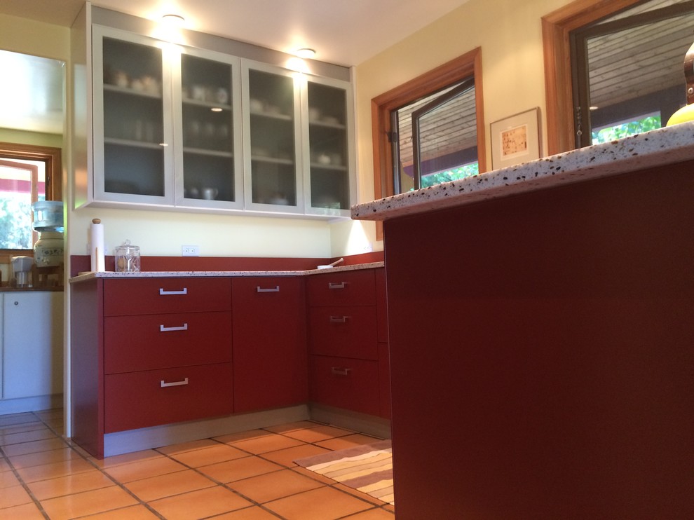 Large contemporary u-shaped kitchen in Vancouver with an undermount sink, flat-panel cabinets, red cabinets, recycled glass benchtops, red splashback and terra-cotta floors.