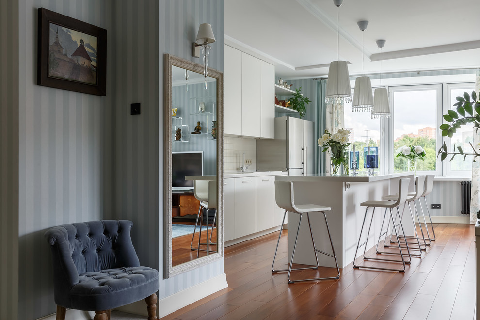 Contemporary single-wall open plan kitchen in Moscow with flat-panel cabinets, white cabinets, white splashback, medium hardwood floors, with island and brown floor.