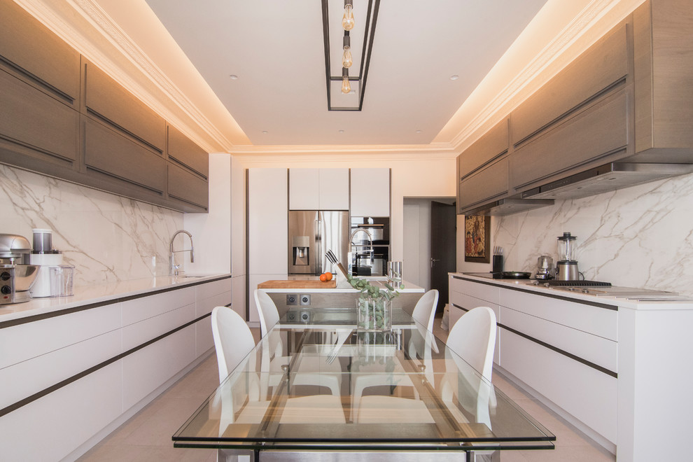 Idées déco pour cuisine in U With un placard à porte plane, des portes de placard blanches, une crédence blanche, un électroménager en acier inoxydable, îlot and un sol gris.