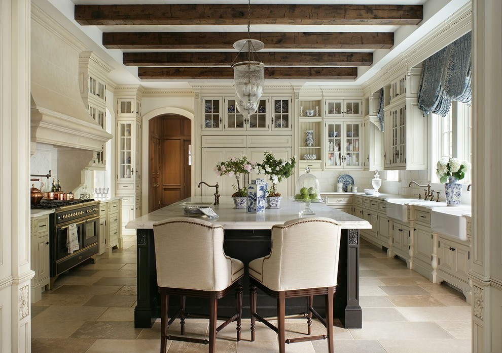 Photo of a traditional u-shaped separate kitchen in New York with a farmhouse sink, raised-panel cabinets, beige cabinets, white splashback, black appliances, with island and beige floor.