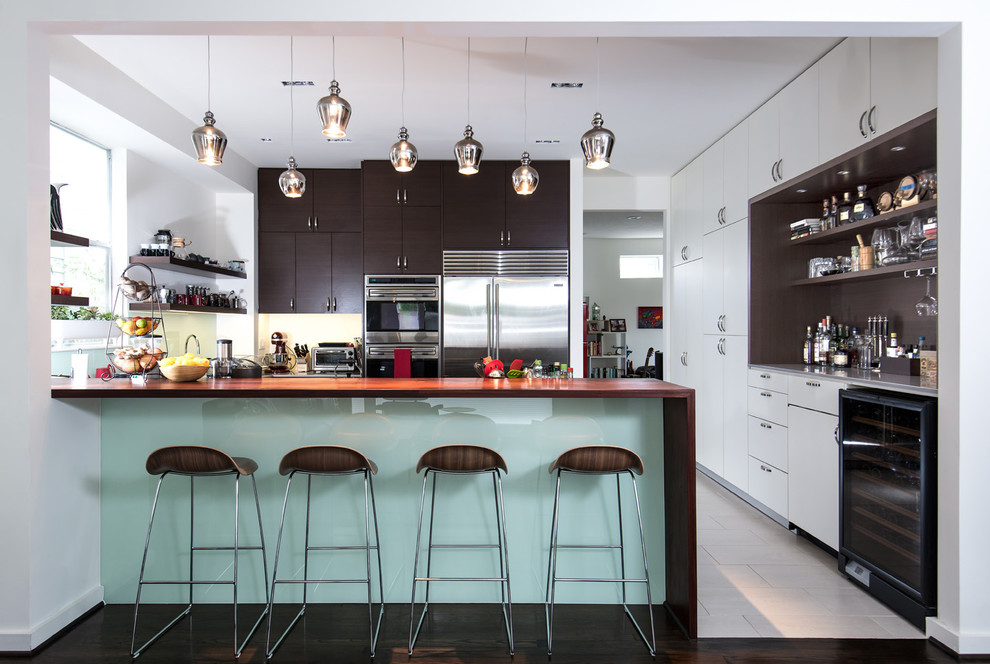 Inspiration for a modern kitchen in Houston with stainless steel appliances, flat-panel cabinets and wood benchtops.