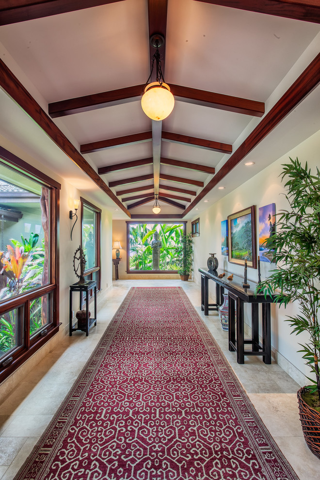 Expansive tropical hallway in Hawaii with travertine floors, white walls and grey floor.