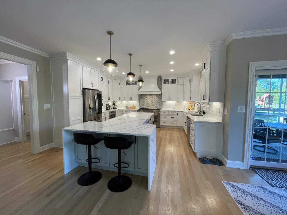 Eat-in kitchen - large contemporary u-shaped beige floor and light wood floor eat-in kitchen idea with white cabinets, gray backsplash, an island, a farmhouse sink, shaker cabinets, quartz countertops, quartz backsplash, stainless steel appliances and white countertops