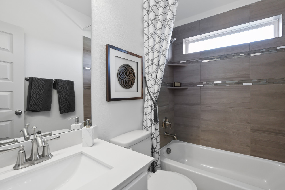 Mid-sized contemporary kids bathroom in Dallas with recessed-panel cabinets, white cabinets, an alcove tub, a shower/bathtub combo, beige tile, ceramic tile, white walls, an undermount sink, solid surface benchtops, a shower curtain and white benchtops.