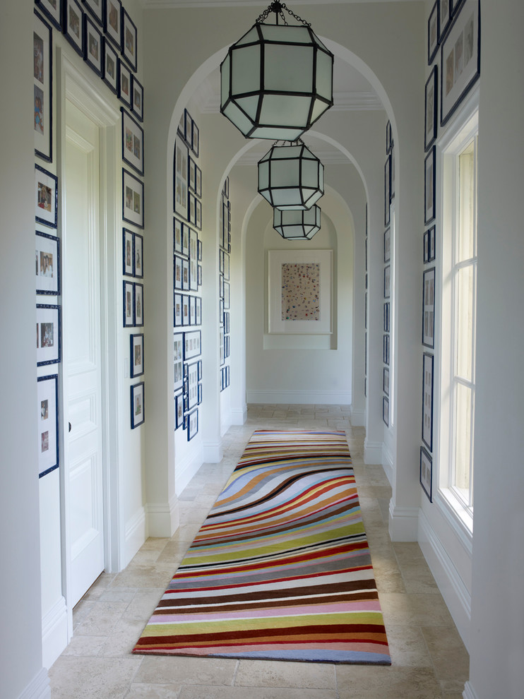 Design ideas for a transitional hallway in Miami with white walls and travertine floors.