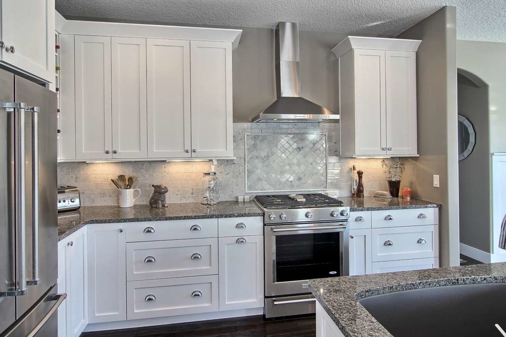 Inspiration for a mid-sized transitional l-shaped dark wood floor open concept kitchen remodel with a single-bowl sink, shaker cabinets, white cabinets, granite countertops, gray backsplash, stone tile backsplash, stainless steel appliances and an island