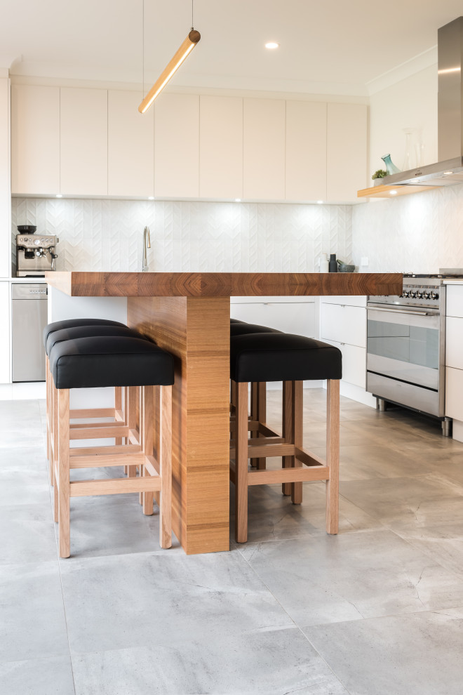 Photo of a mid-sized industrial l-shaped eat-in kitchen in Adelaide with an undermount sink, flat-panel cabinets, white cabinets, quartz benchtops, white splashback, mosaic tile splashback, stainless steel appliances, cement tiles, with island, grey floor and white benchtop.