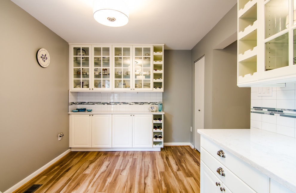 Example of a mid-sized transitional l-shaped vinyl floor enclosed kitchen design in DC Metro with an undermount sink, shaker cabinets, quartz countertops, white backsplash, ceramic backsplash, black appliances and no island
