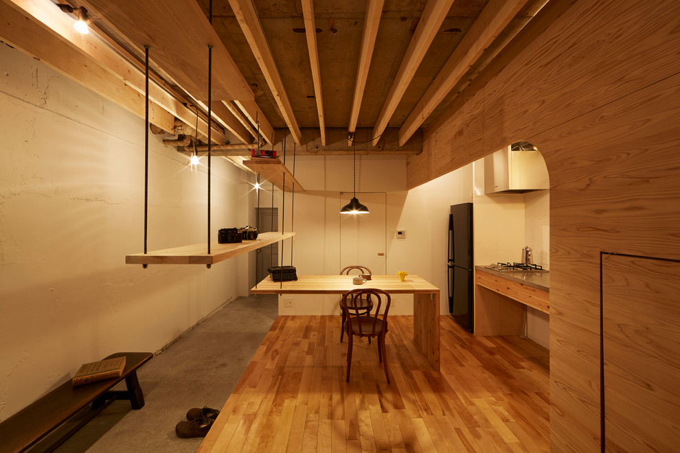 Design ideas for a mid-sized industrial open plan dining in Tokyo with white walls, medium hardwood floors and brown floor.