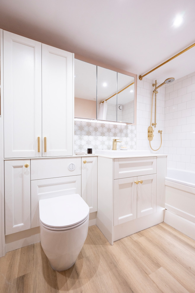 Design ideas for a small classic family bathroom in Kent with shaker cabinets, white cabinets, a built-in bath, a shower/bath combination, a one-piece toilet, white tiles, porcelain tiles, pink walls, solid surface worktops, a shower curtain, white worktops, feature lighting, a single sink and a built in vanity unit.