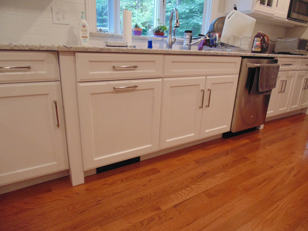 Mid-sized transitional medium tone wood floor and brown floor eat-in kitchen photo with an undermount sink, recessed-panel cabinets, white cabinets, granite countertops, white backsplash, subway tile backsplash, stainless steel appliances, no island and white countertops