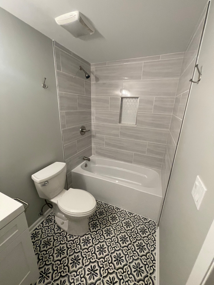 Inredning av ett modernt mellanstort vit vitt en-suite badrum, med skåp i shakerstil, vita skåp, ett badkar i en alkov, en dusch/badkar-kombination, en toalettstol med separat cisternkåpa, grå kakel, porslinskakel, grå väggar, mosaikgolv, ett integrerad handfat, bänkskiva i akrylsten och dusch med duschdraperi