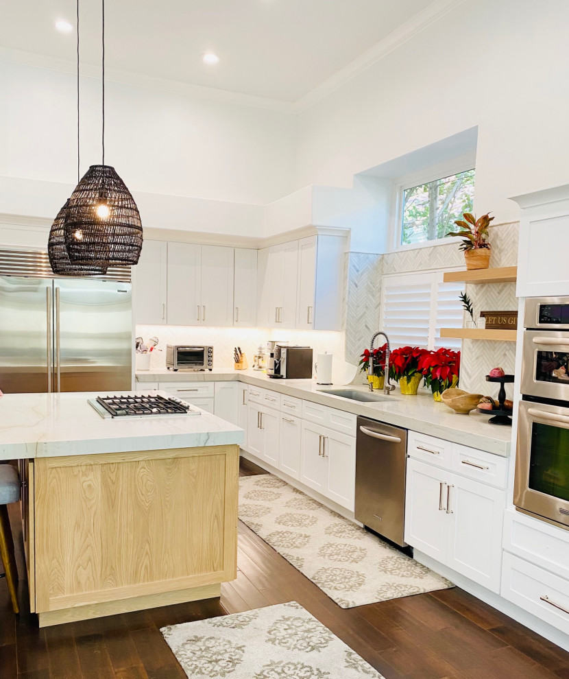 Traditional kitchen in Orange County with an undermount sink, shaker cabinets, white cabinets, quartzite benchtops, white splashback, marble splashback, stainless steel appliances, dark hardwood floors, with island and white benchtop.