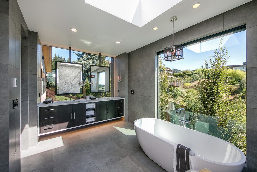 Photo of a contemporary master bathroom in Seattle with flat-panel cabinets, black cabinets, a freestanding tub, gray tile, grey walls, an undermount sink and grey floor.