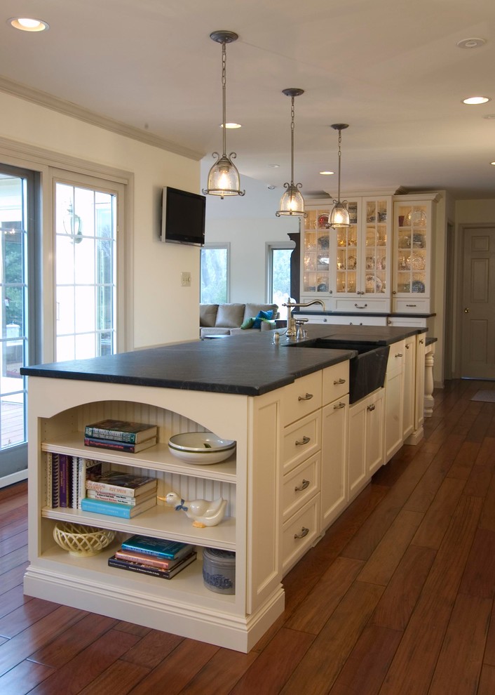 Inspiration for an expansive country galley separate kitchen in Philadelphia with a farmhouse sink, recessed-panel cabinets, beige cabinets, soapstone benchtops, beige splashback, stone tile splashback, stainless steel appliances, medium hardwood floors and with island.