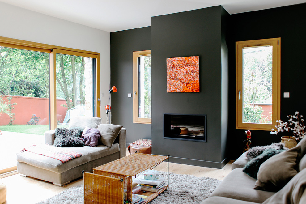 This is an example of a contemporary open concept living room in Paris with grey walls, light hardwood floors, a standard fireplace and a metal fireplace surround.