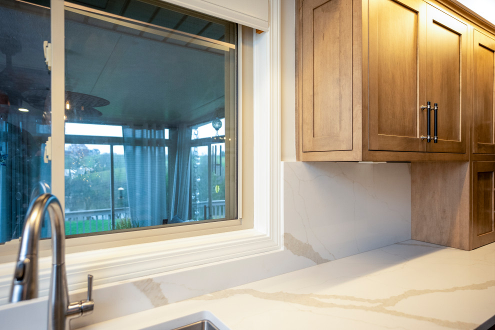 Example of a large transitional l-shaped medium tone wood floor and brown floor eat-in kitchen design with a single-bowl sink, shaker cabinets, medium tone wood cabinets, quartz countertops, white backsplash, quartz backsplash, stainless steel appliances, an island and white countertops