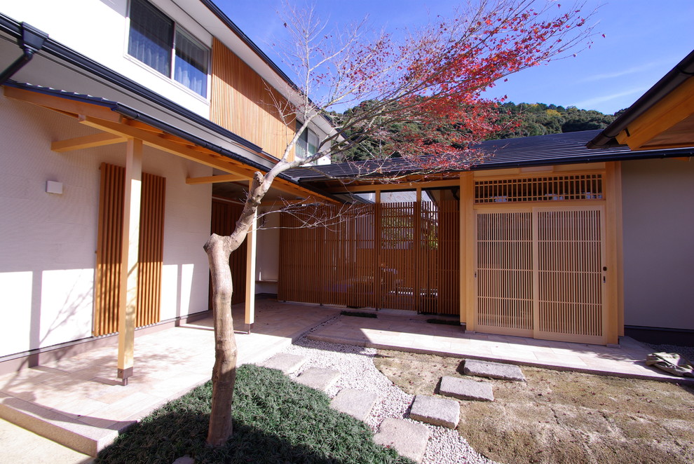 Asian front yard patio in Kyoto with decomposed granite and a roof extension.