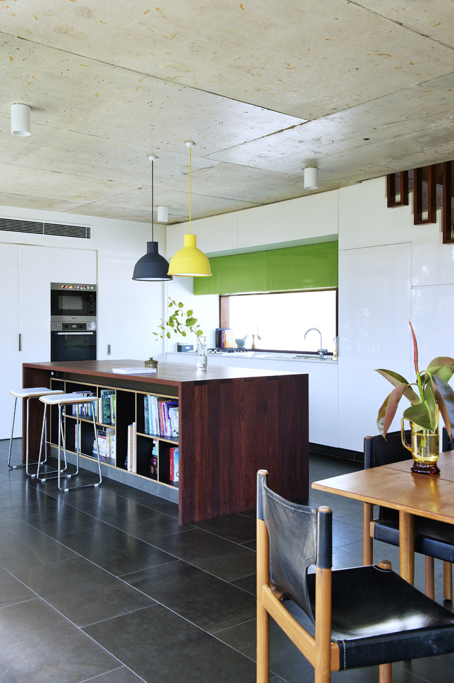 Photo of a mid-sized midcentury eat-in kitchen in Perth with flat-panel cabinets, white cabinets, stainless steel appliances and with island.