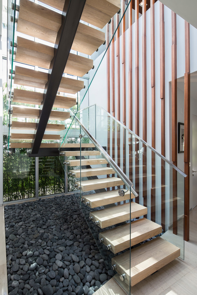 Photo of a contemporary wood u-shaped staircase in Miami with open risers and glass railing.