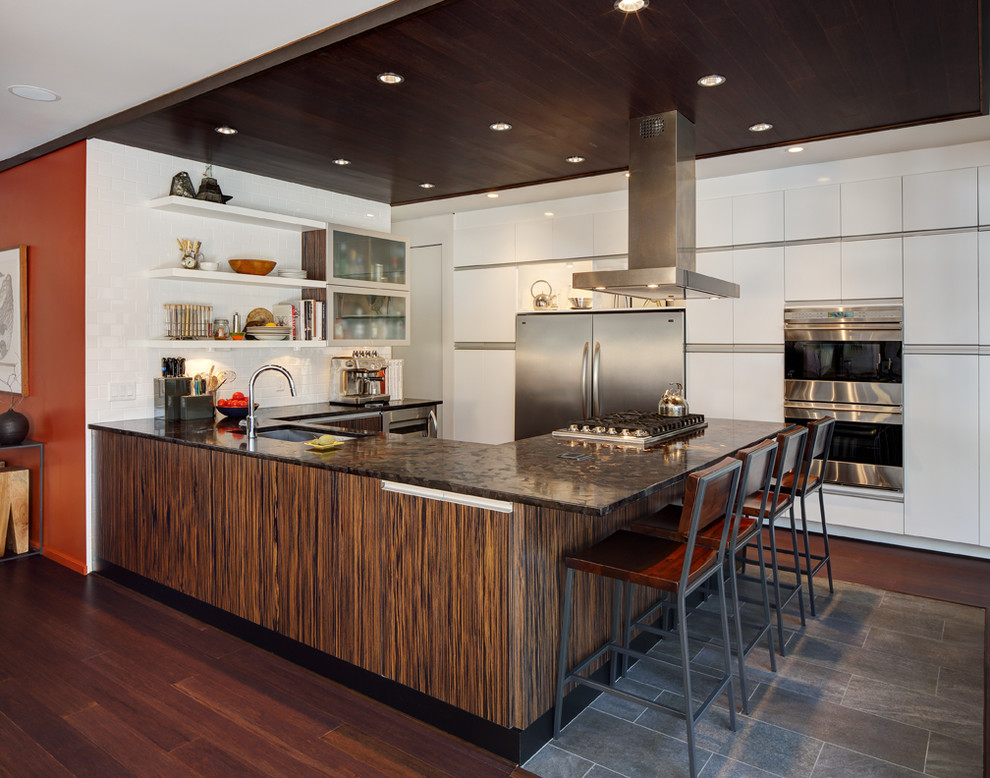 Design ideas for a contemporary u-shaped kitchen in Milwaukee with flat-panel cabinets, white cabinets, white splashback, stainless steel appliances, an undermount sink and dark hardwood floors.